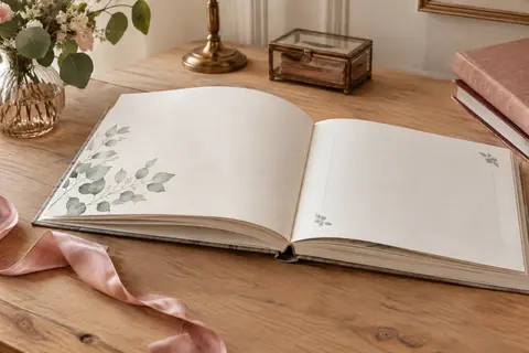 Livre d’or de mariage à couverture rigide avec motif d’eucalyptus, ouvert sur une table claire