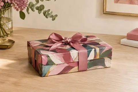 Coffret cadeau rectangulaire multicolore posé sur une table en bois dans un intérieur lumineux et raffiné.